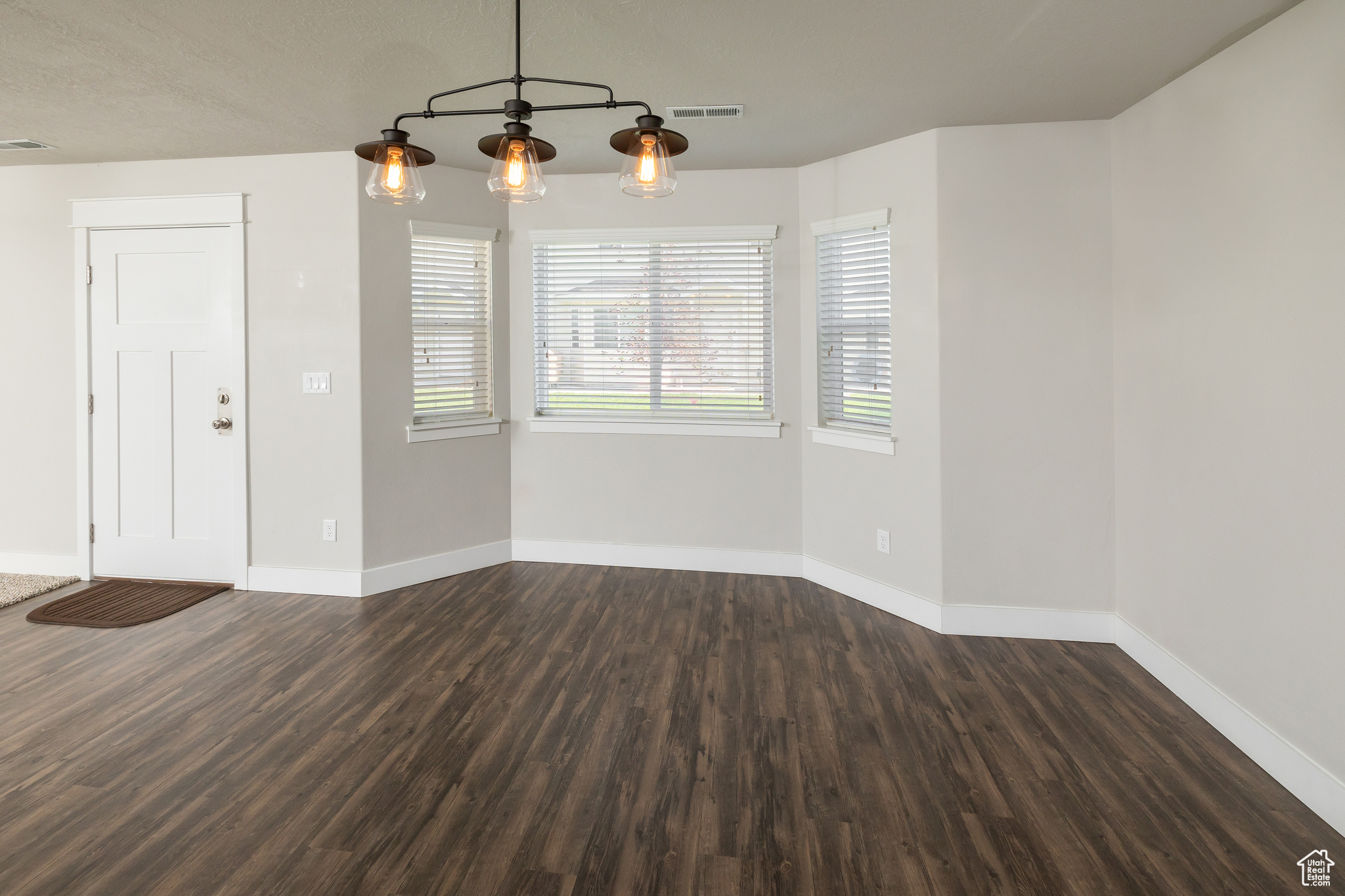 Empty room with dark hardwood / wood-style flooring and a healthy amount of sunlight