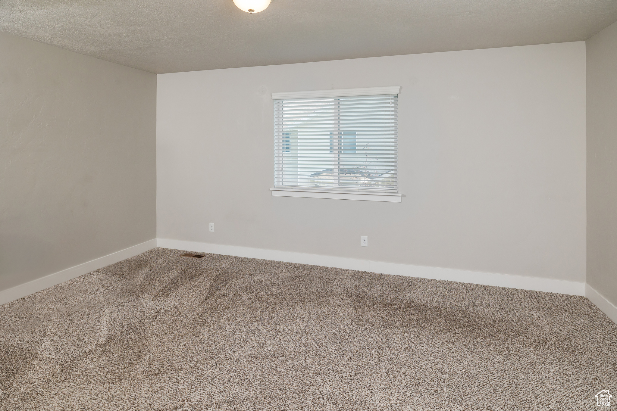 Carpeted empty room featuring a textured ceiling