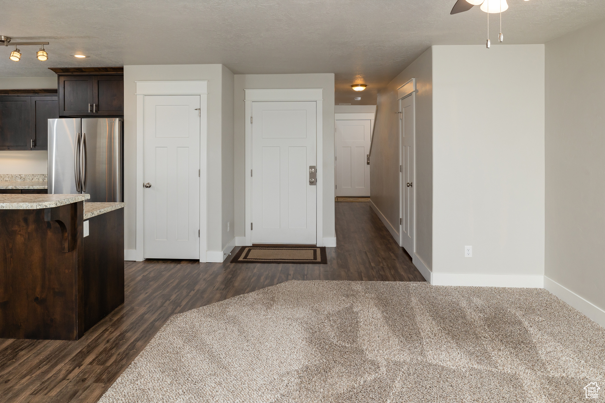 Kitchen featuring ceiling fan, dark wood-type flooring, stainless steel refrigerator, and rail lighting