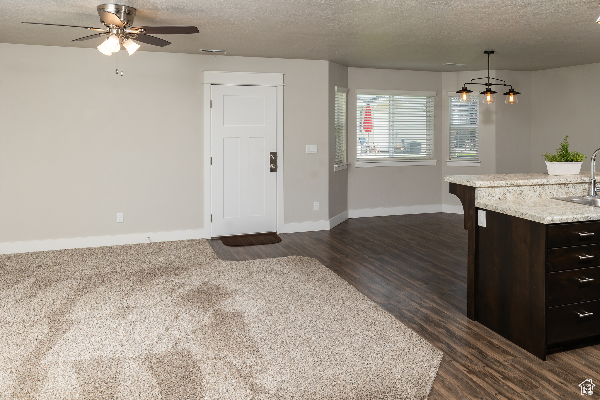 Kitchen featuring decorative light fixtures, dark brown cabinets, ceiling fan, sink, and dark carpet