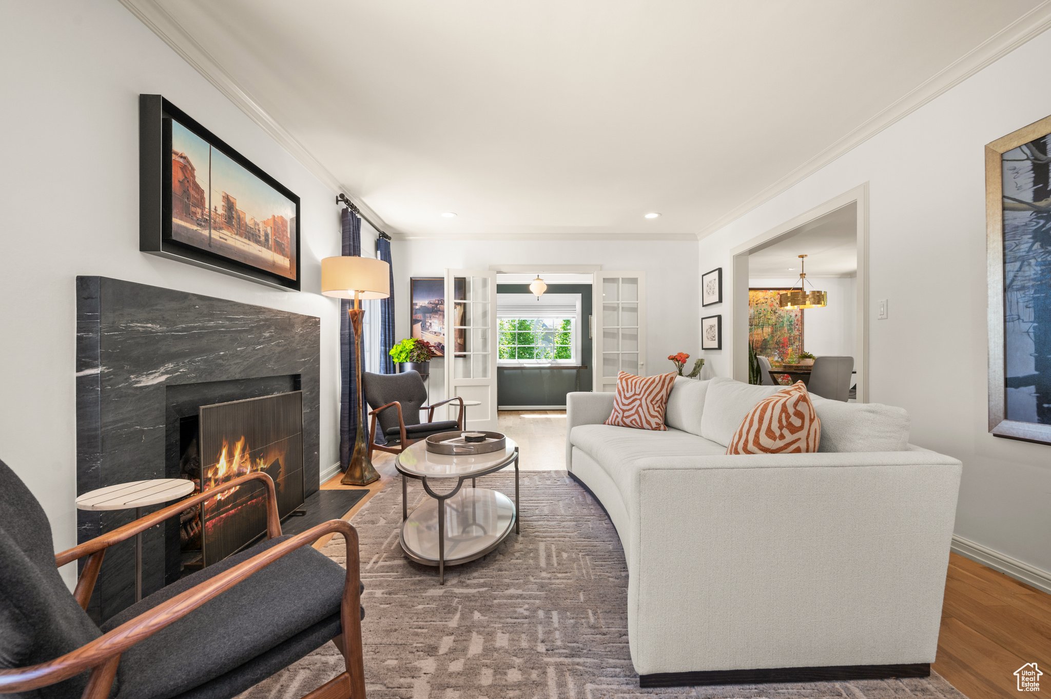 Living room featuring a premium fireplace, a chandelier, hardwood  flooring, and ornamental molding