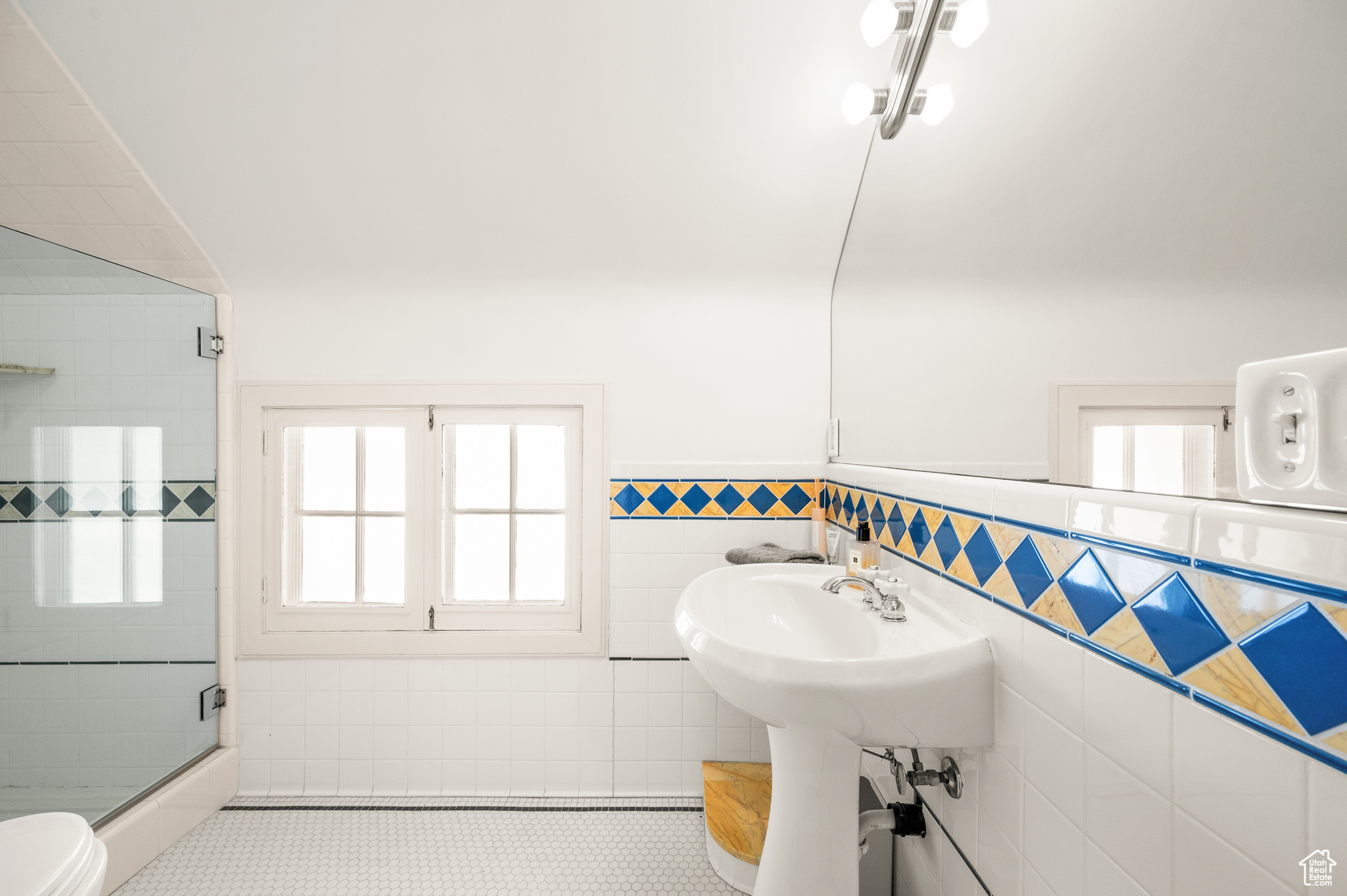 Bathroom featuring a wealth of natural light, tile patterned flooring, toilet, and tile walls