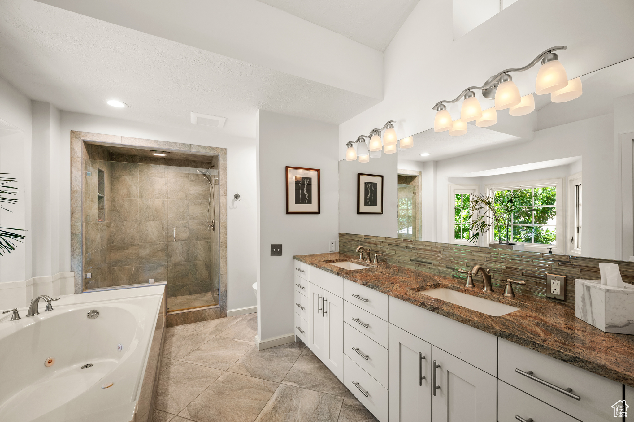 Primary Bathroom featuring double vanity, plus walk-in shower, tasteful backsplash, and tile patterned floors