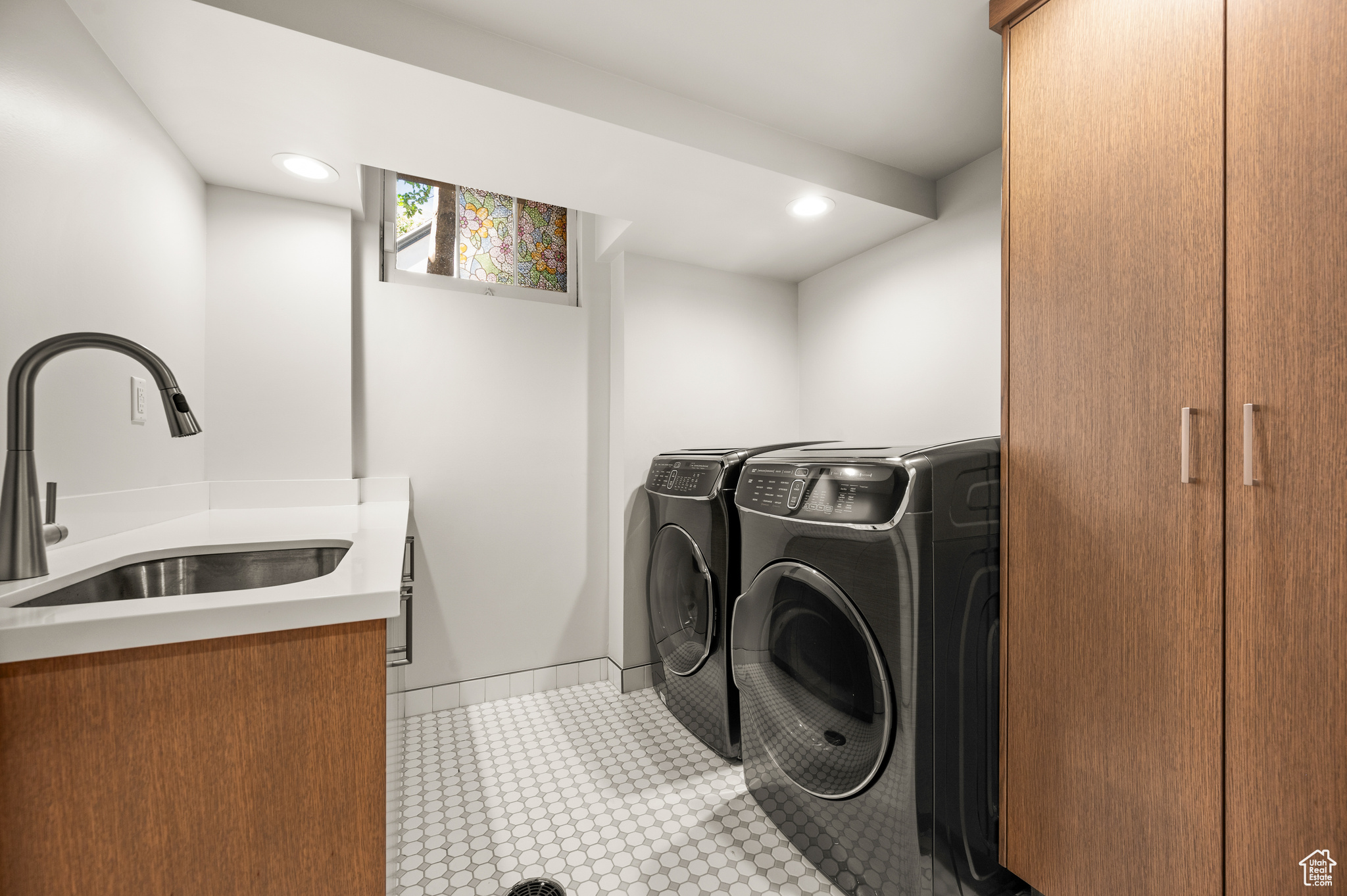 Clothes washing area featuring cabinets, separate washer and dryer, sink, and light tile patterned floors