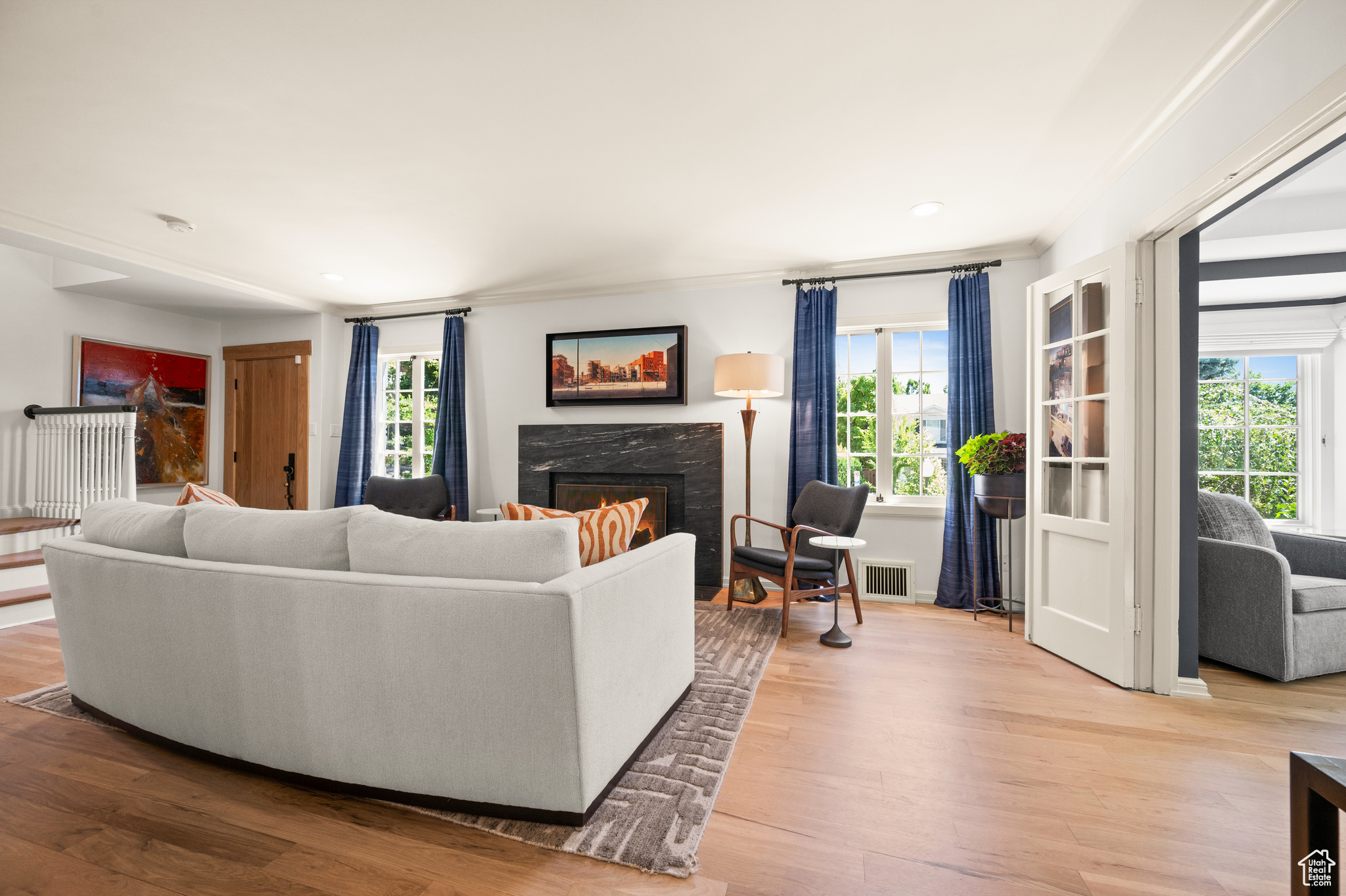 Living room with light hardwood / wood floors, crown molding, and a premium fireplace