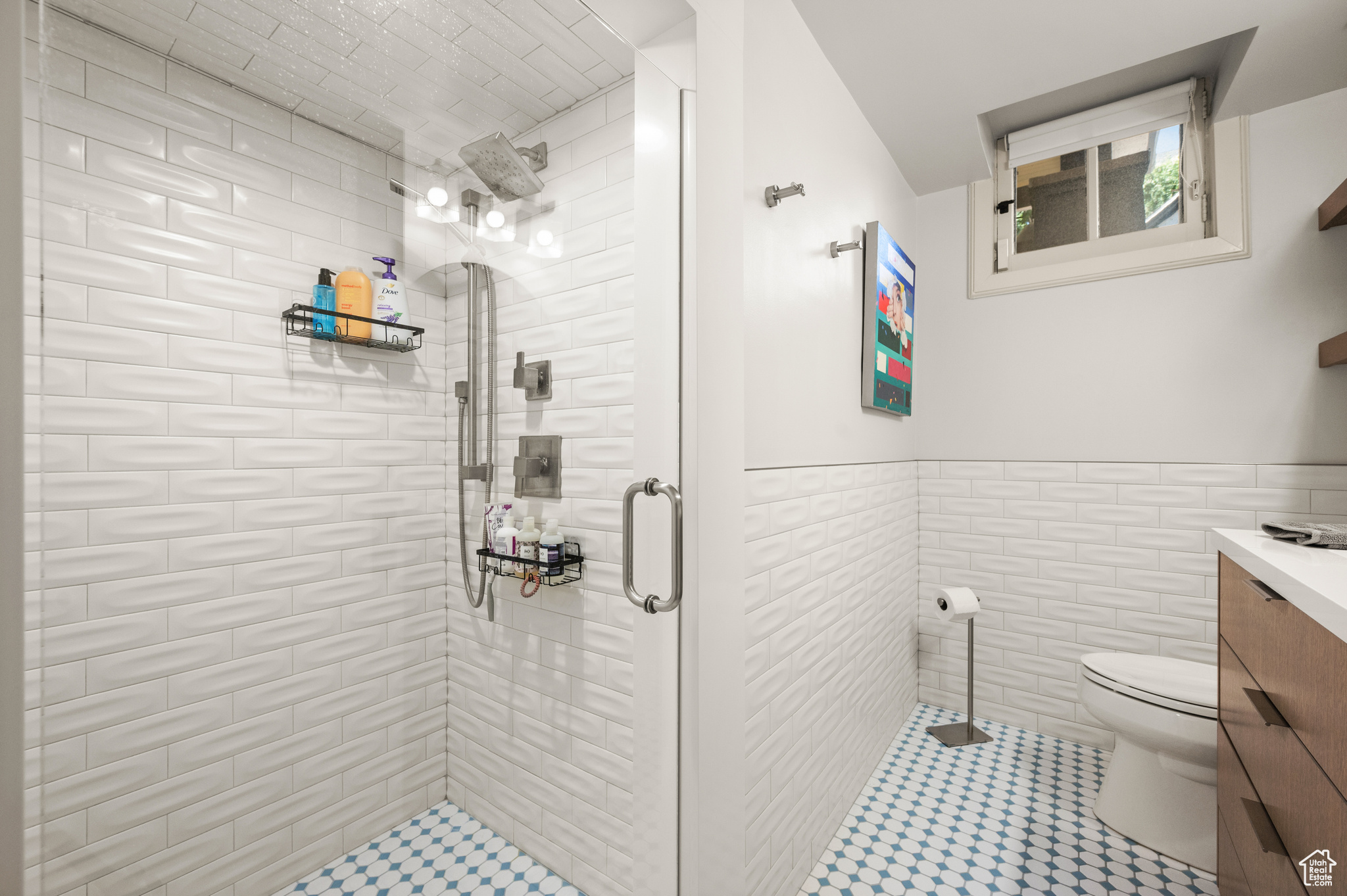 Bathroom featuring vanity, tile walls, toilet, a shower with door, and tile patterned flooring