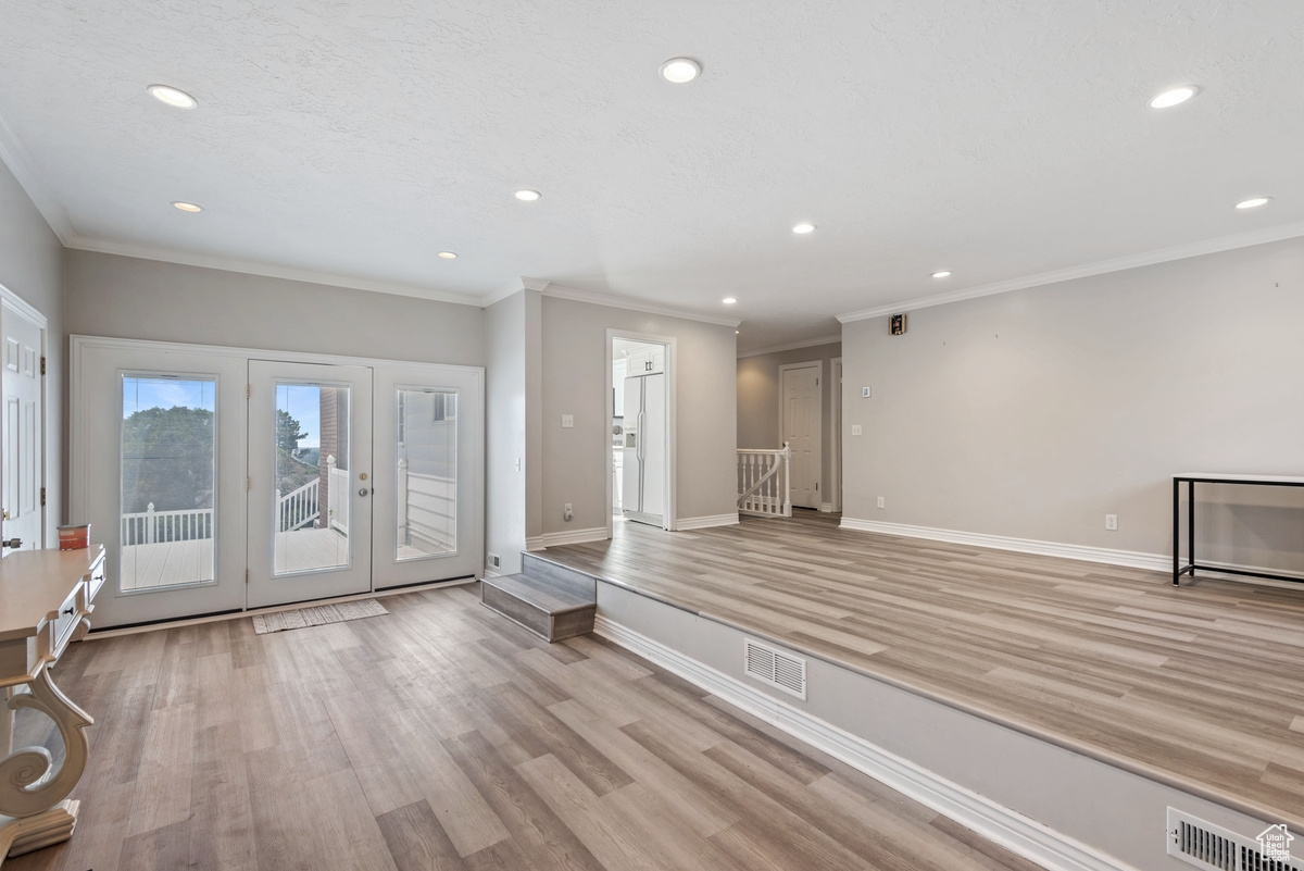 Foyer with light wood-type flooring and ornamental molding