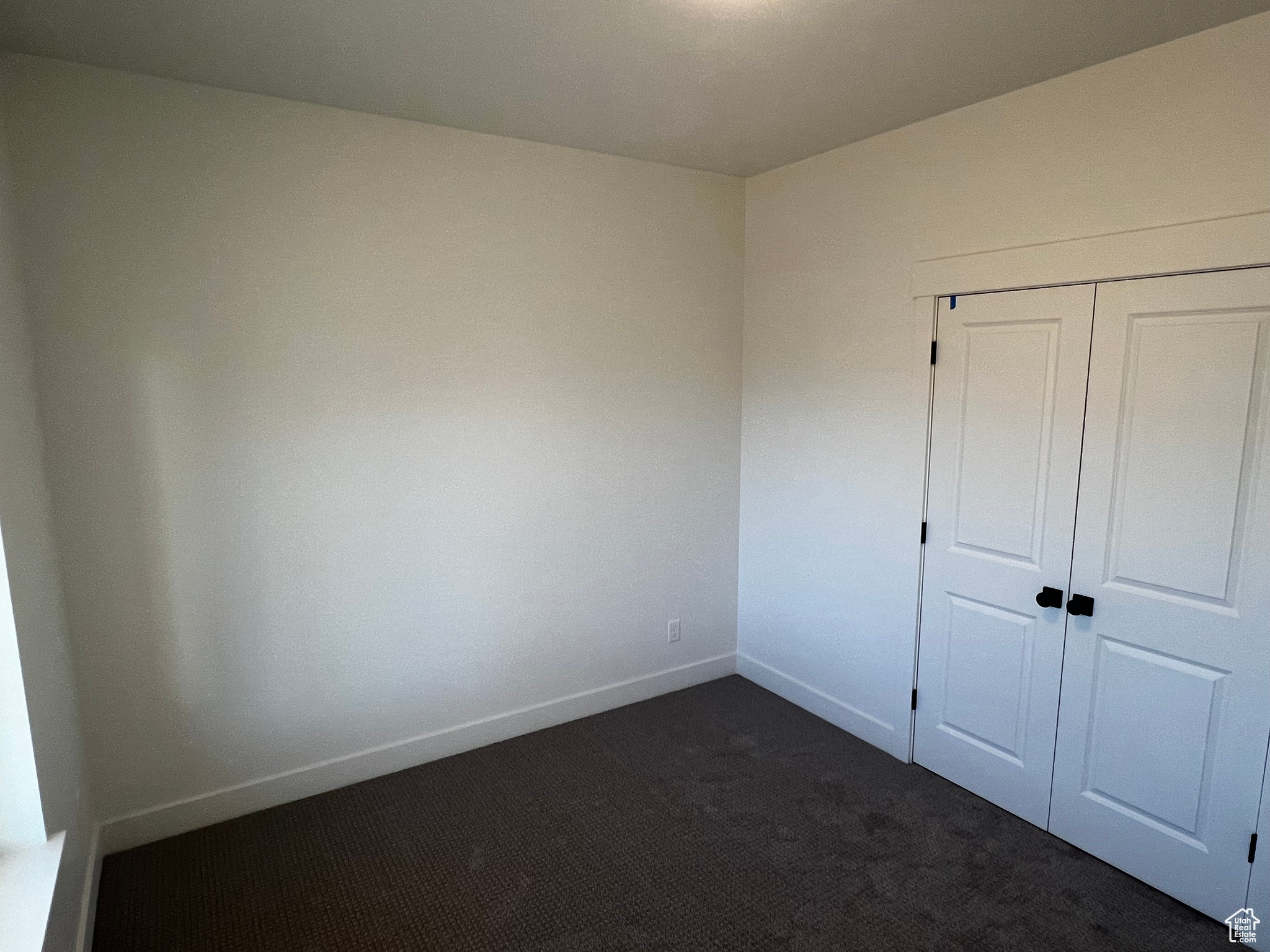 Unfurnished bedroom with a closet and dark carpet