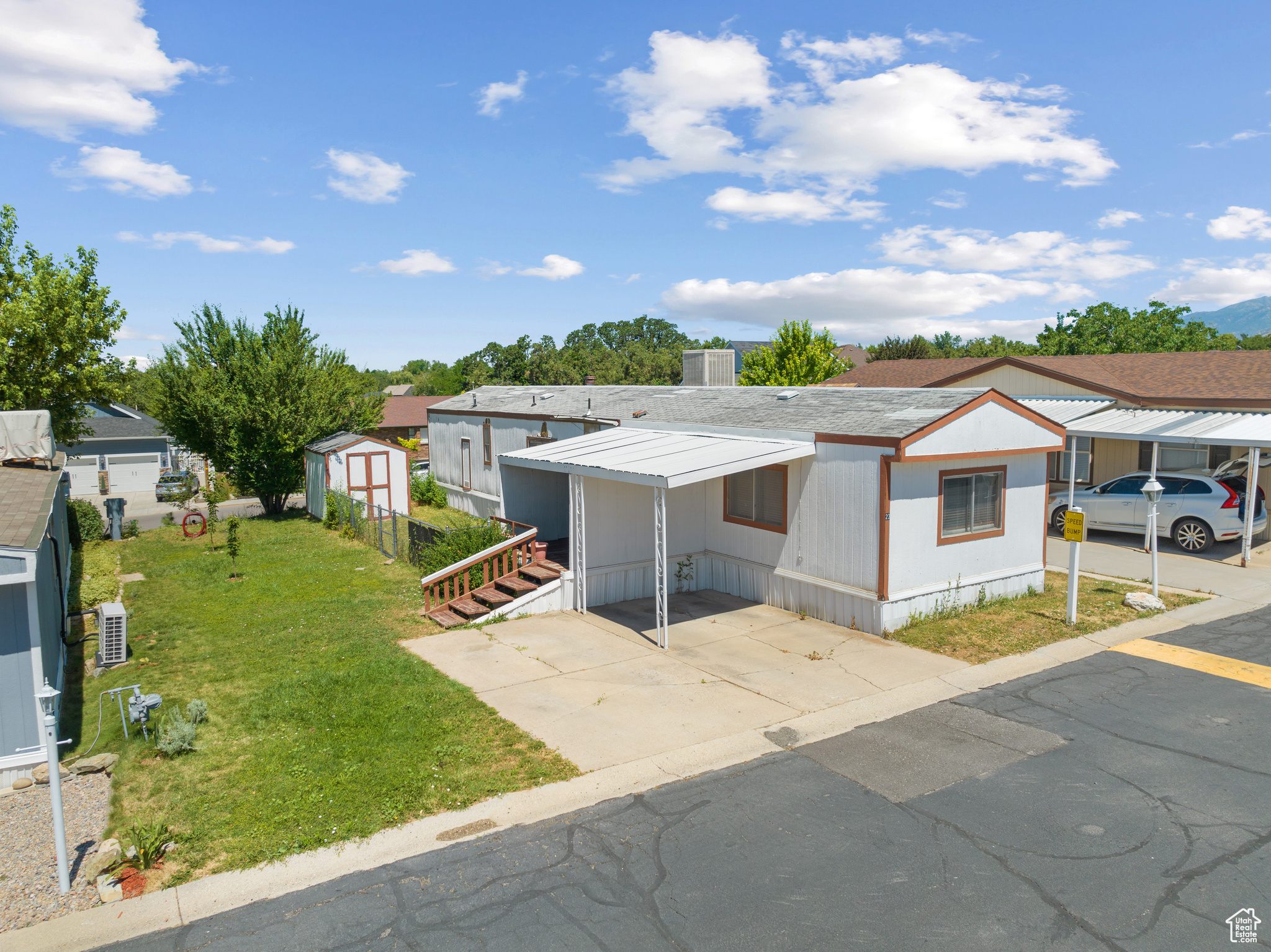 Manufactured / mobile home featuring a front lawn, a storage unit, and a carport