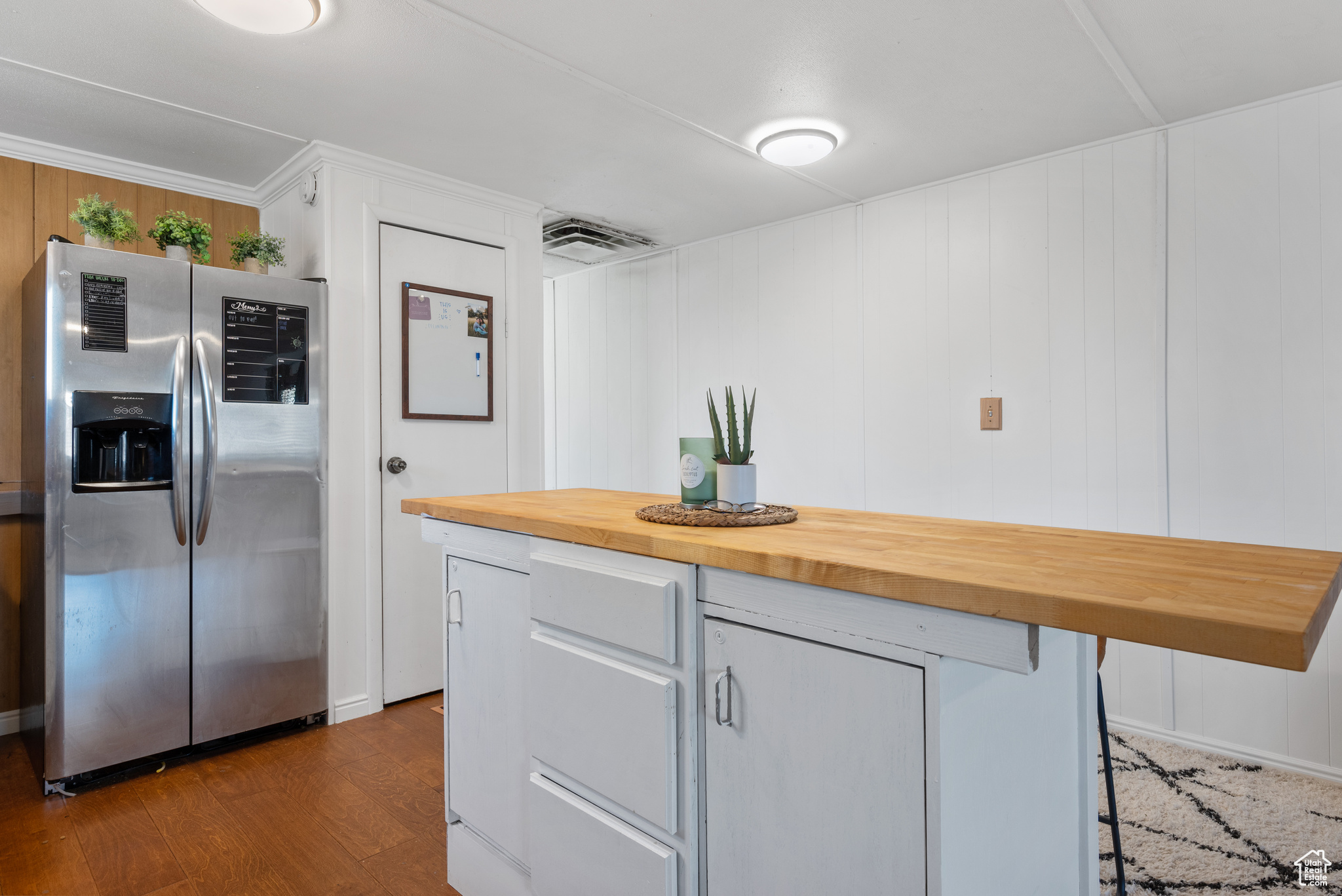 Kitchen with butcher block counters, stainless steel fridge with ice dispenser, hardwood / wood-style floors, a kitchen bar, and gray cabinetry