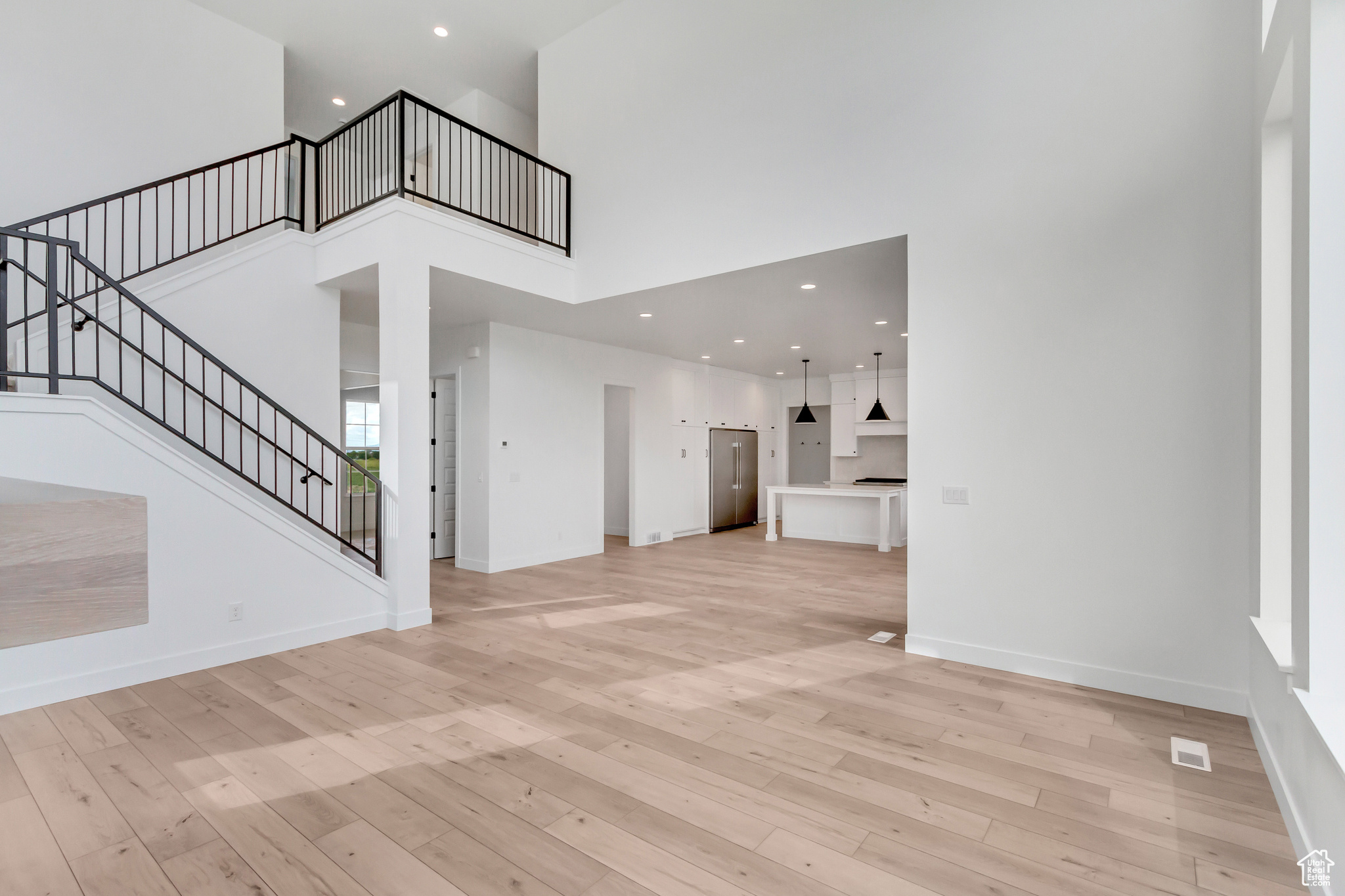 Unfurnished living room featuring a towering ceiling and light hardwood / wood-style flooring