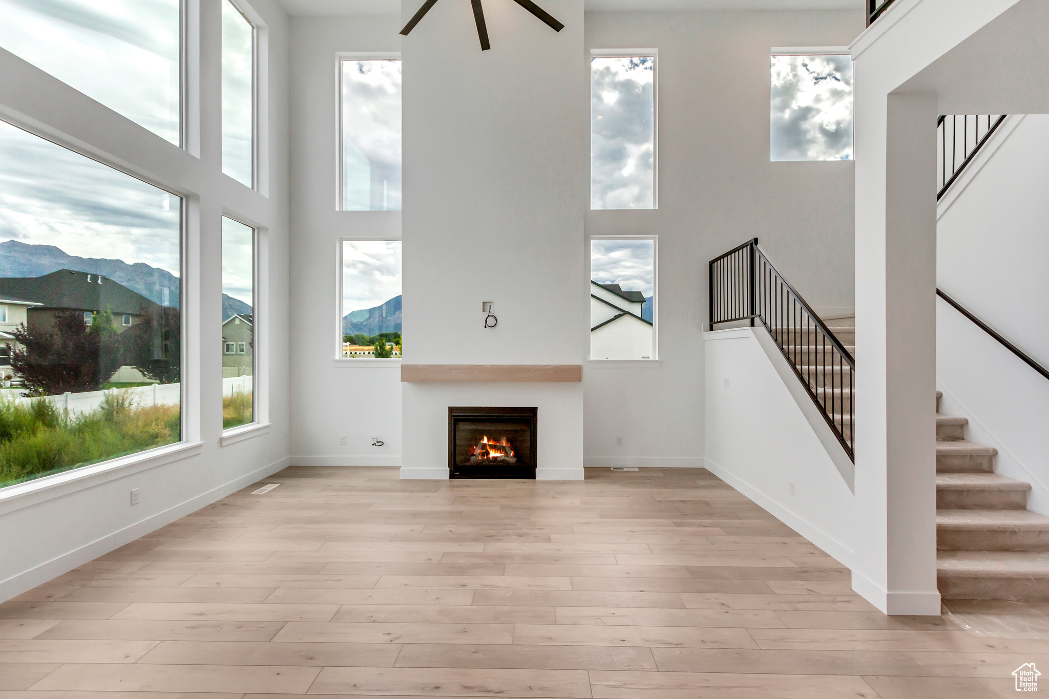 Unfurnished living room featuring light wood-type flooring, a mountain view, and a high ceiling