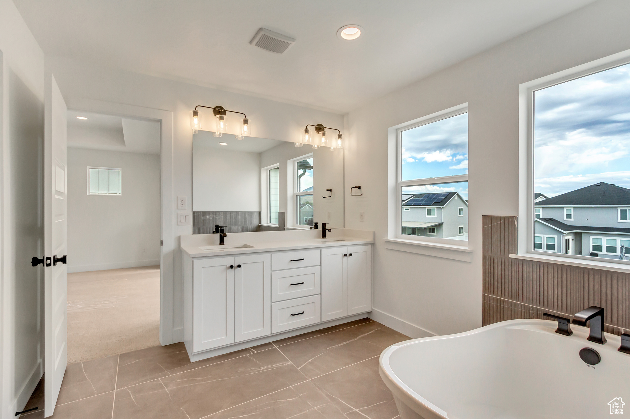 Bathroom featuring tile patterned flooring, a bath, and vanity