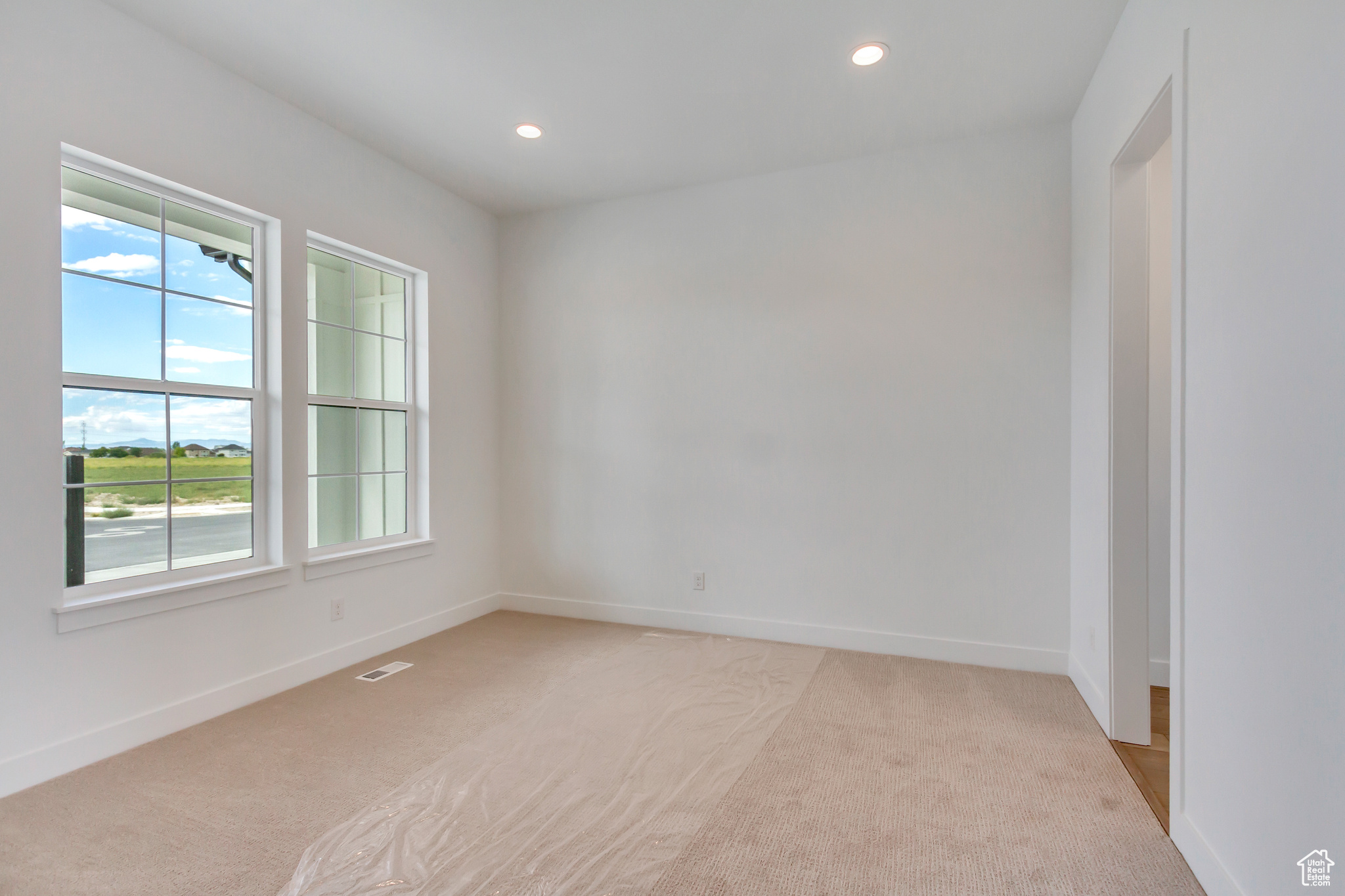 Empty room with light colored carpet and a healthy amount of sunlight