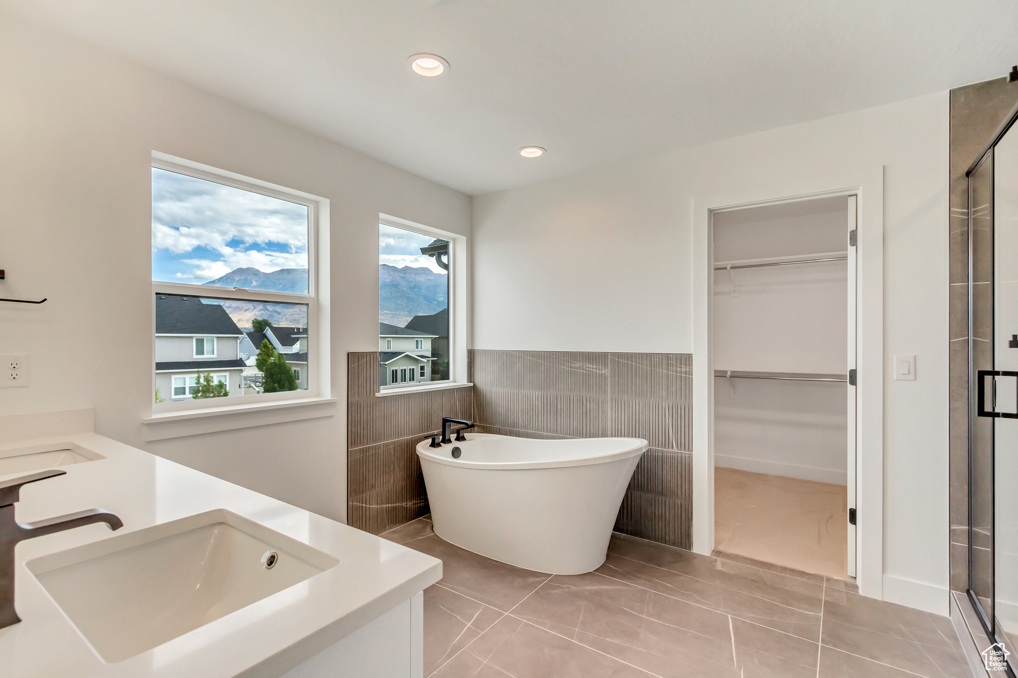 Bathroom with tile patterned flooring, tile walls, independent shower and bath, and vanity