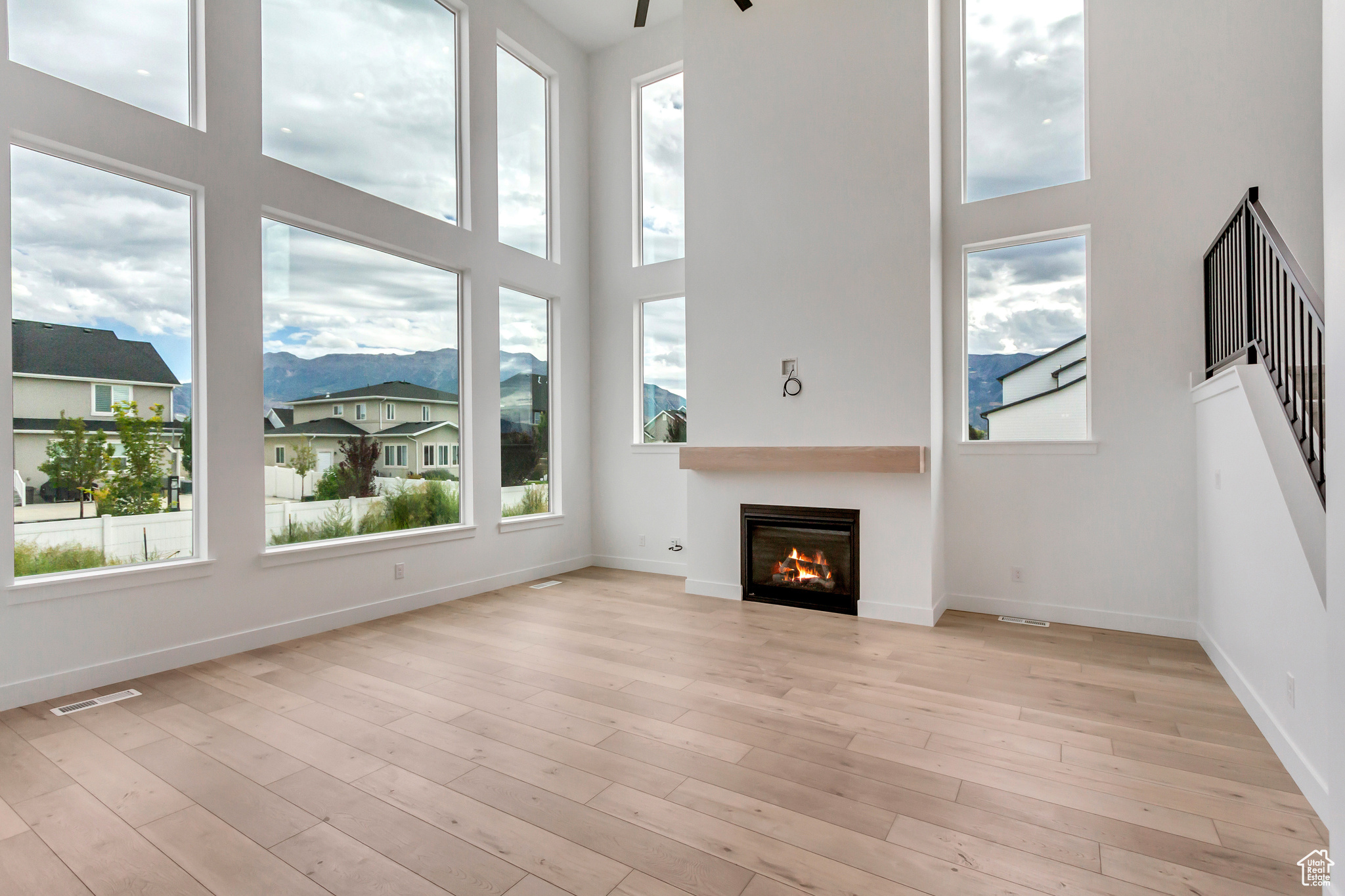 Unfurnished living room with light hardwood / wood-style floors, a high ceiling, and plenty of natural light