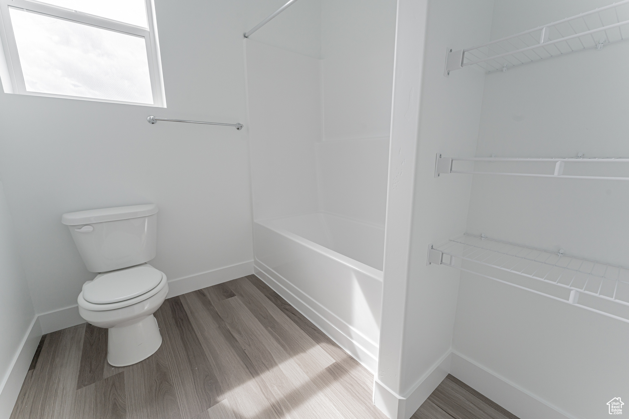 Bathroom with hardwood / wood-style floors, tub / shower combination, and toilet