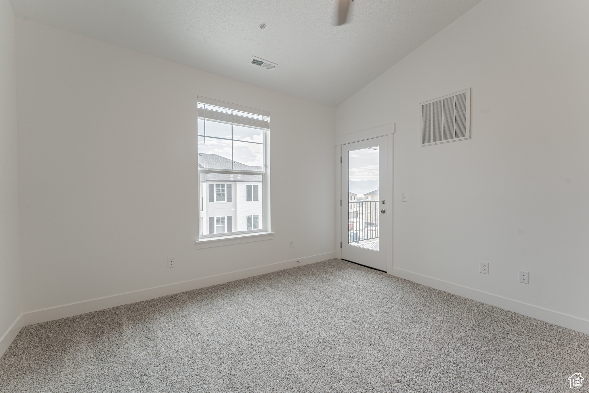 Carpeted spare room featuring plenty of natural light and lofted ceiling