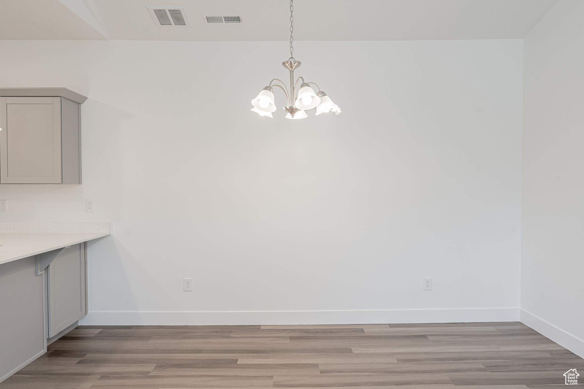 Unfurnished dining area featuring light wood-type flooring and a notable chandelier