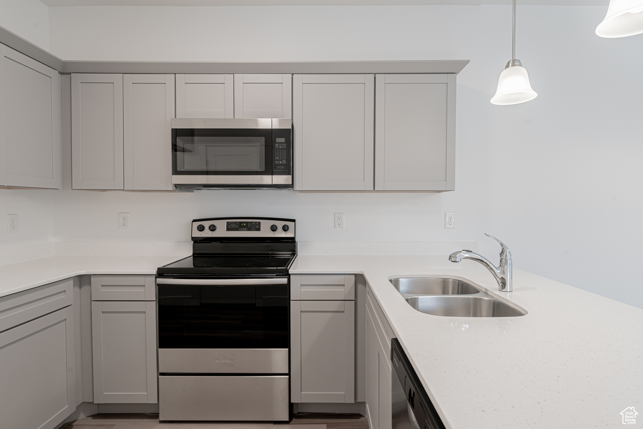 Kitchen with sink, stainless steel appliances, gray cabinetry, and hanging light fixtures