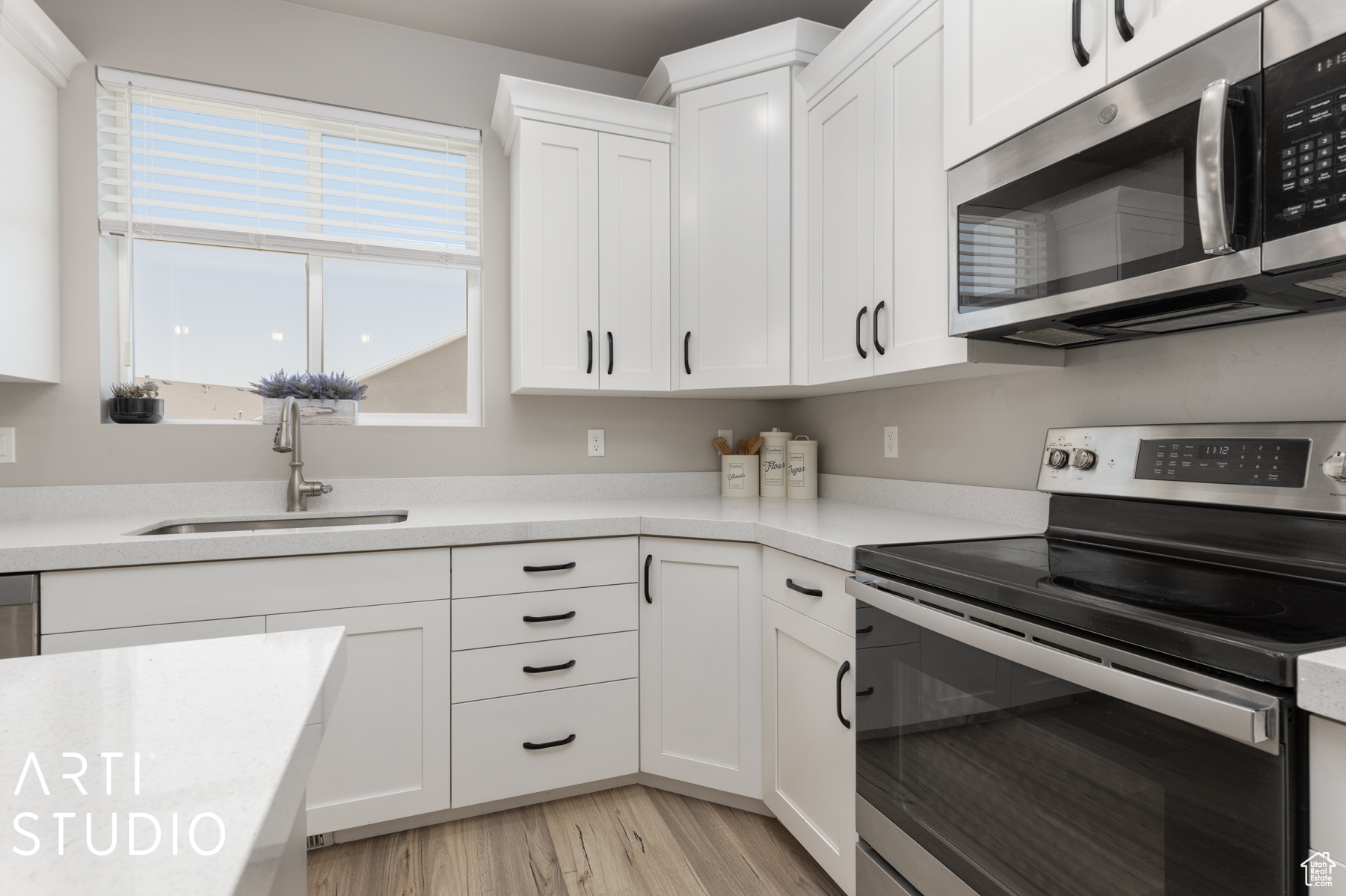 Kitchen with sink, light hardwood / wood-style flooring, stainless steel appliances, and white cabinetry