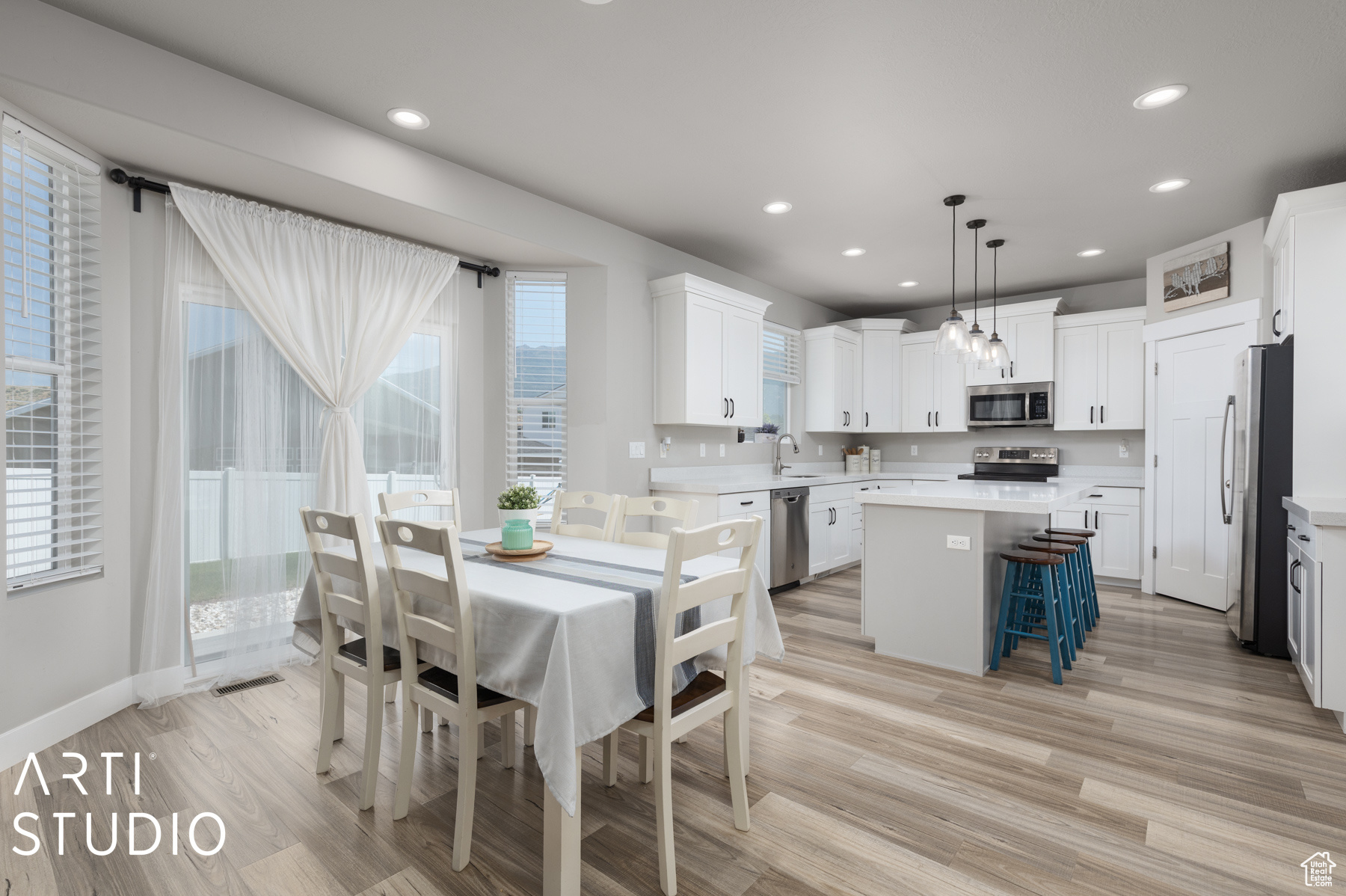 Kitchen with light wood-type flooring, a kitchen island, stainless steel appliances, pendant lighting, and sink