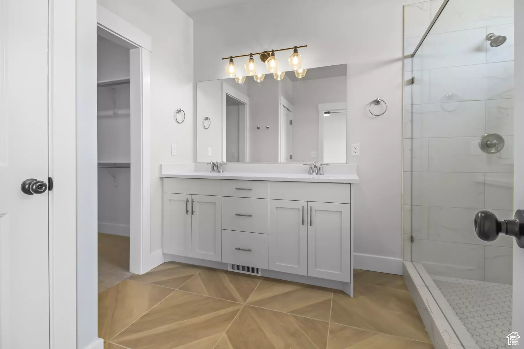 Bathroom with dual vanity, tiled shower, and tile patterned flooring