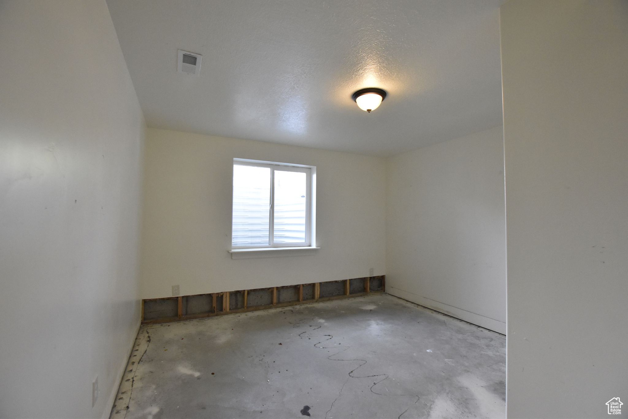 Empty room featuring a textured ceiling and concrete floors