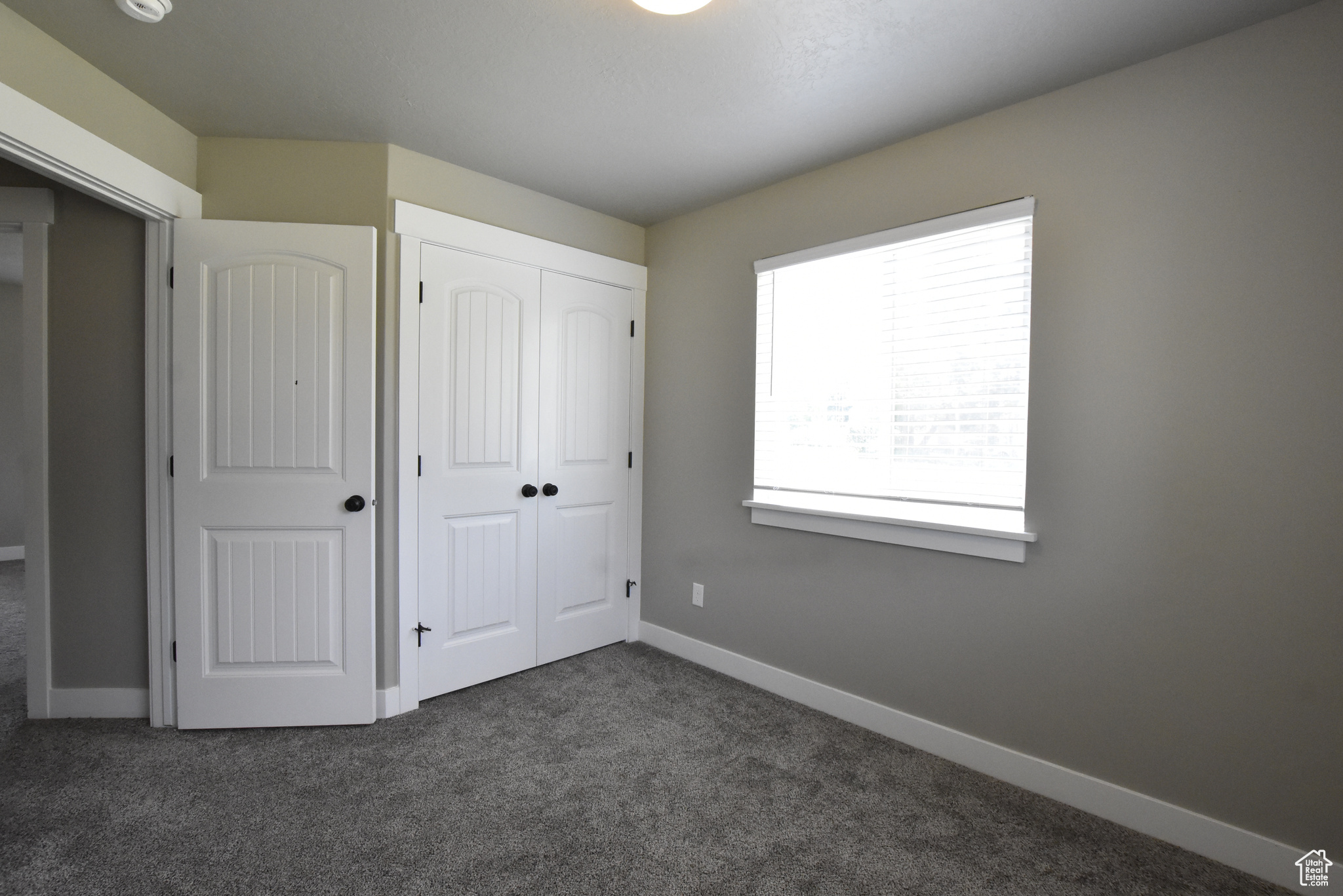 Unfurnished bedroom featuring dark carpet and a closet