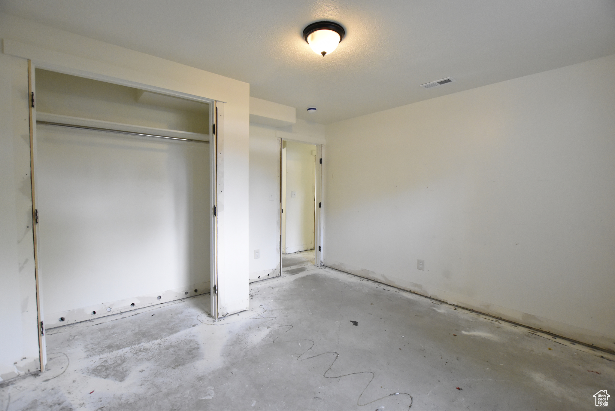 Unfurnished bedroom featuring concrete flooring and a closet