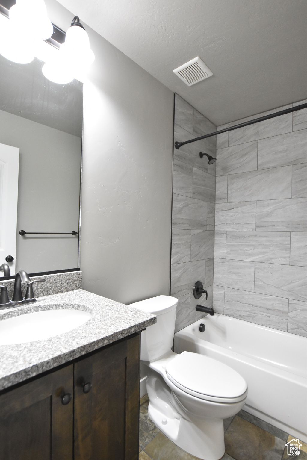 Full bathroom featuring vanity, tile patterned flooring, tiled shower / bath combo, and toilet