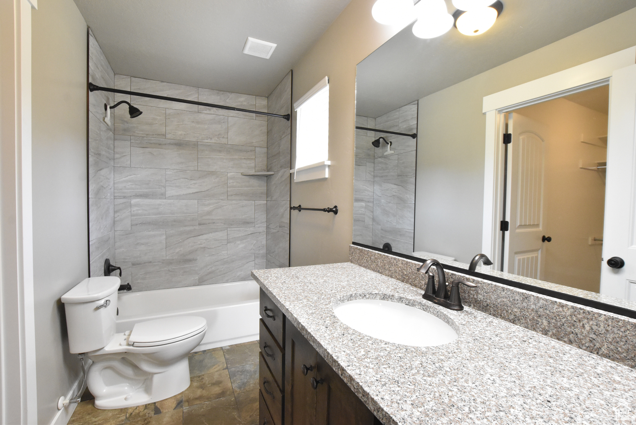 Full bathroom with vanity, tile patterned flooring, tiled shower / bath, and toilet