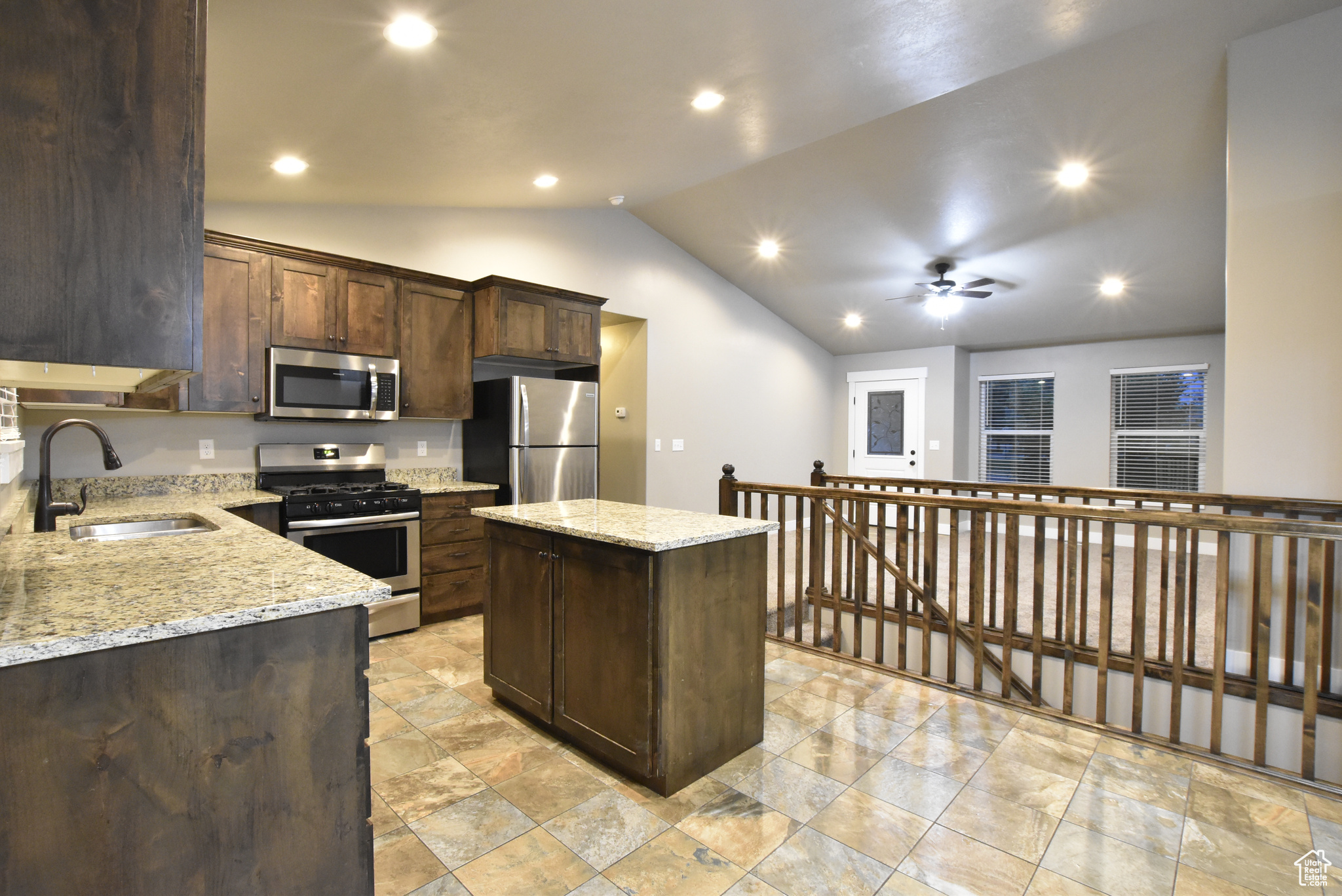 Kitchen featuring ceiling fan, stainless steel appliances, sink, a center island, and lofted ceiling