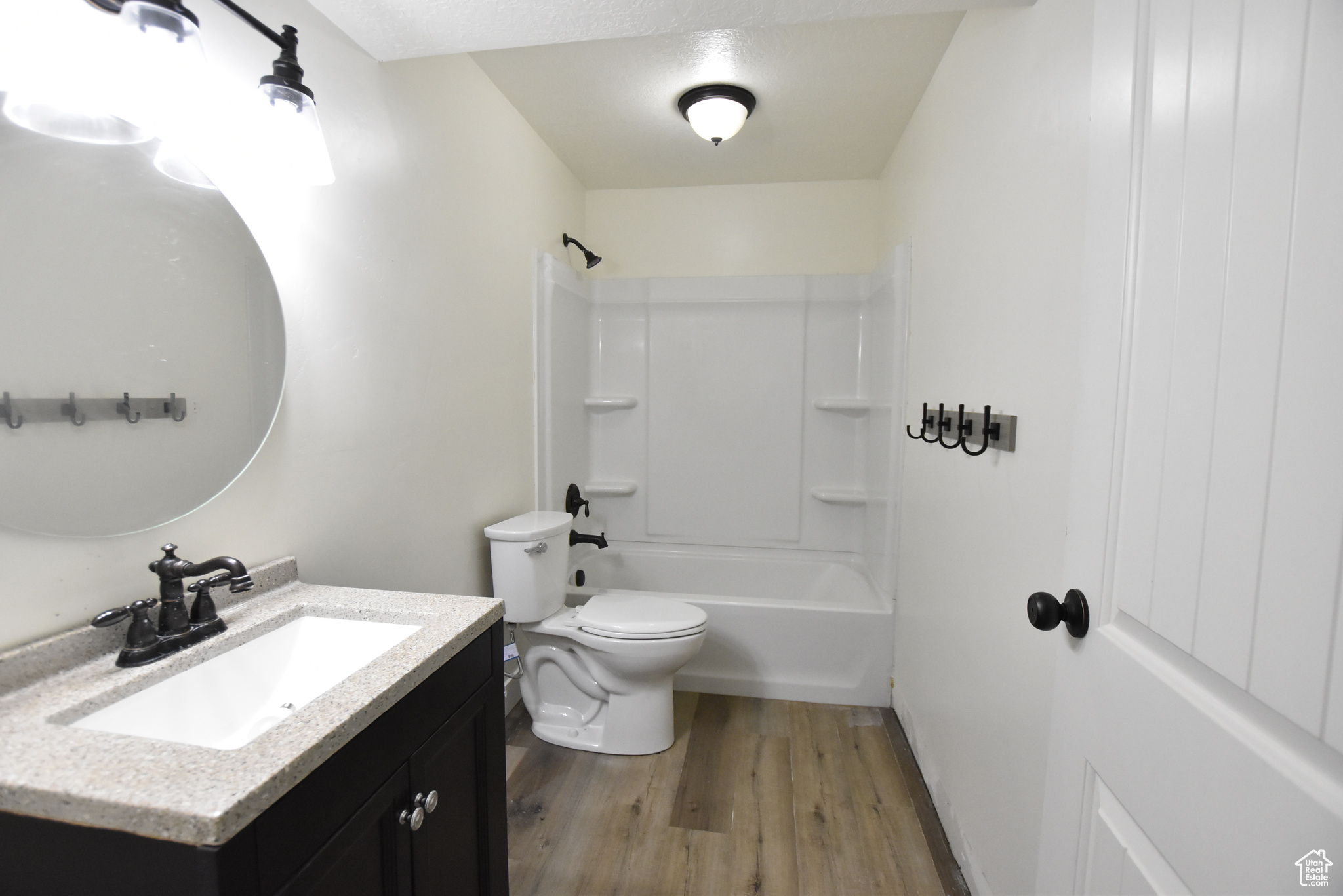 Full bathroom with vanity, wood-type flooring, shower / tub combination, toilet, and a textured ceiling