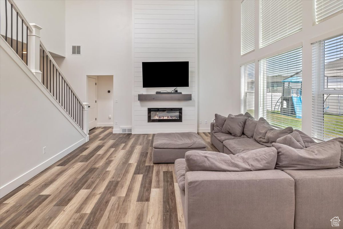 Living room with a fireplace, hardwood / wood-style floors, and a high ceiling