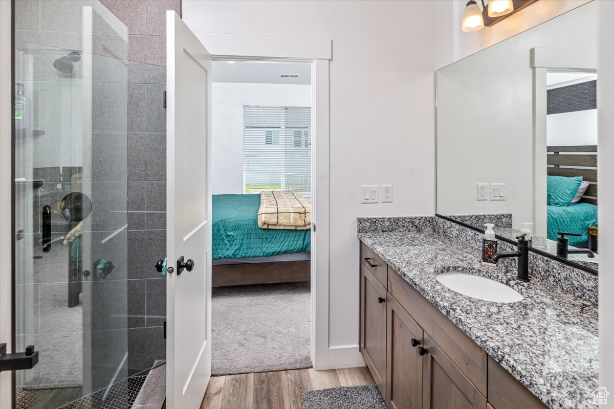 Bathroom with vanity, a tile shower, and hardwood / wood-style flooring