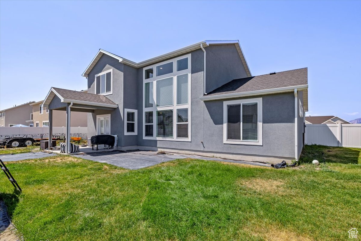 Rear view of property with a patio and a lawn