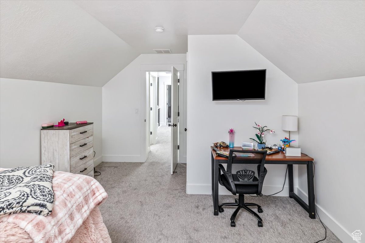 Bedroom with light carpet, a textured ceiling, and vaulted ceiling