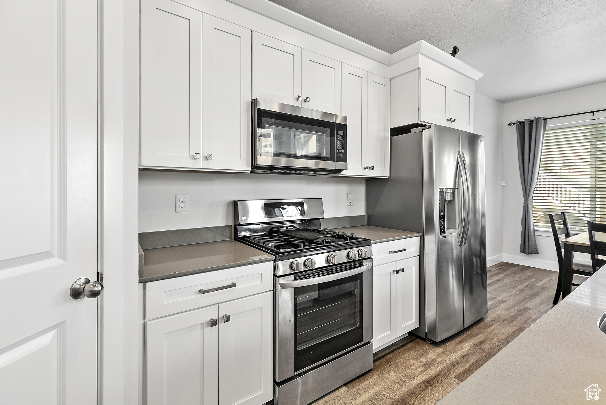 Kitchen featuring white cabinets,, wood-style flooring, and appliances with stainless steel finishes