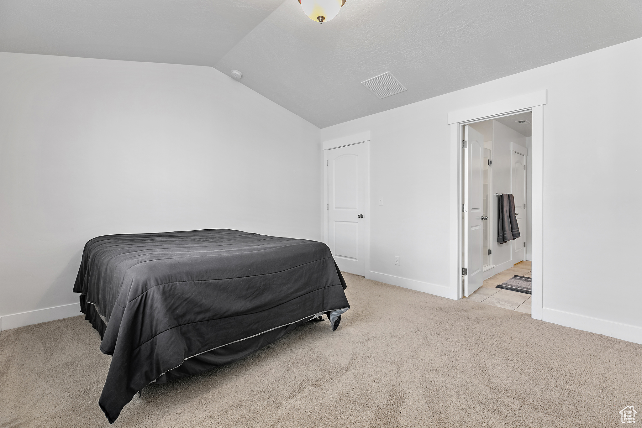 Bedroom with light carpet and vaulted ceiling