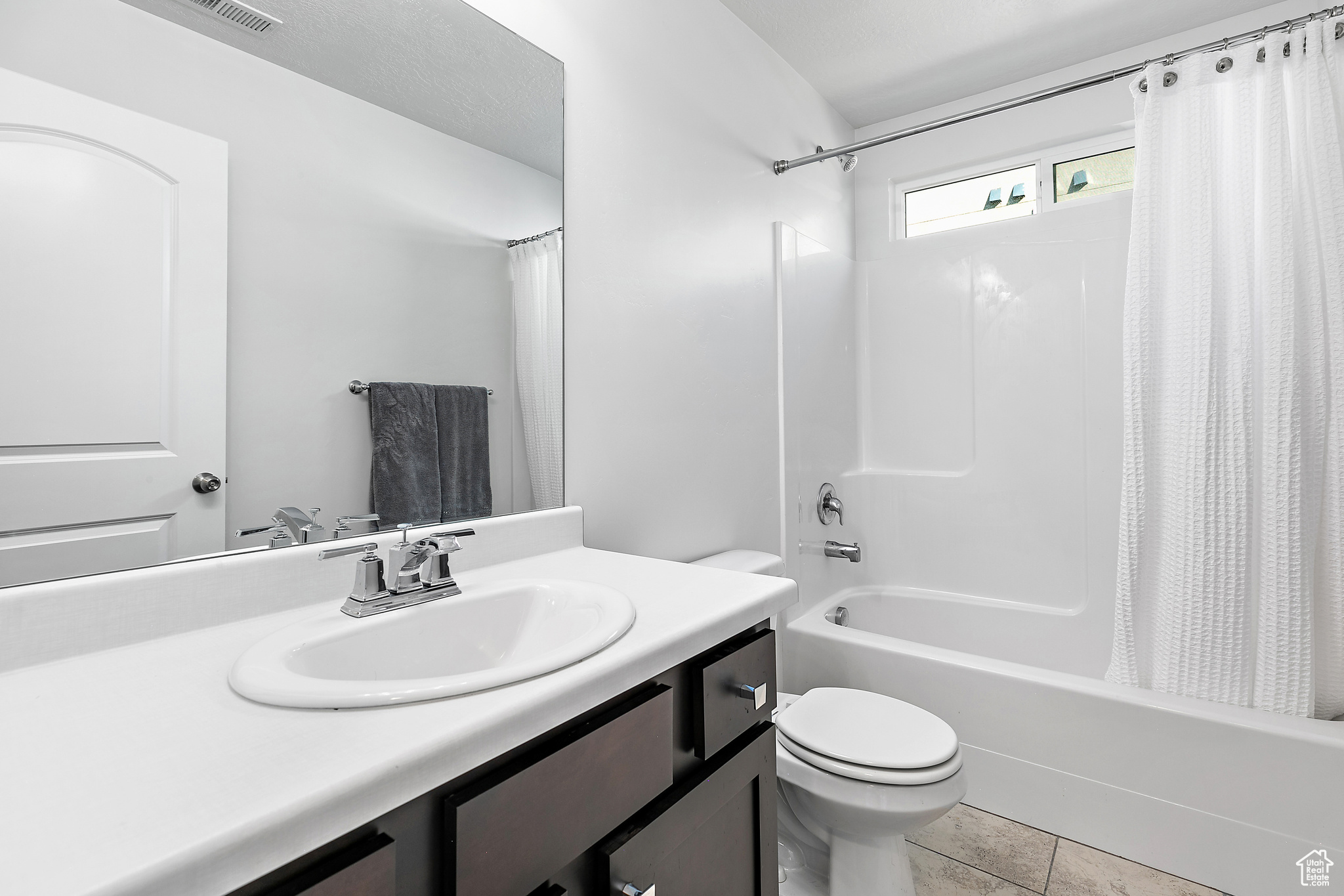 Full bathroom featuring shower / tub combo with curtain, vanity, tile patterned flooring, and toilet