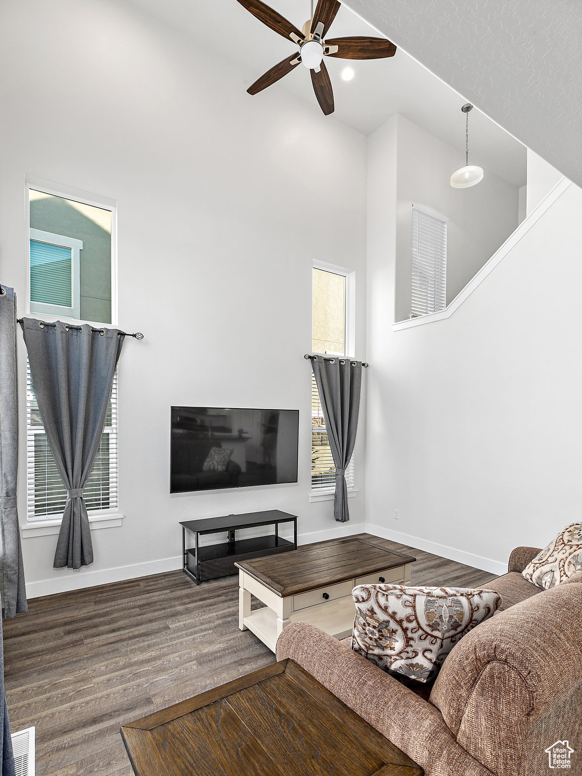 Living room with wood-style floors, a high ceiling, and ceiling fan