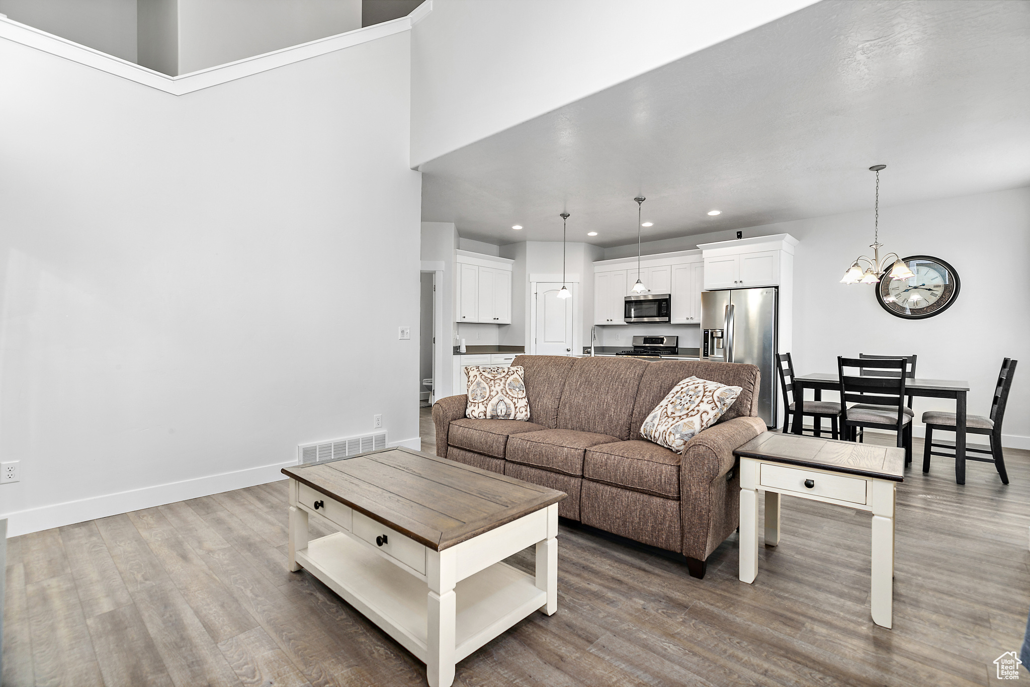 Living room with wood-type flooring, a notable chandelier, and a towering ceiling