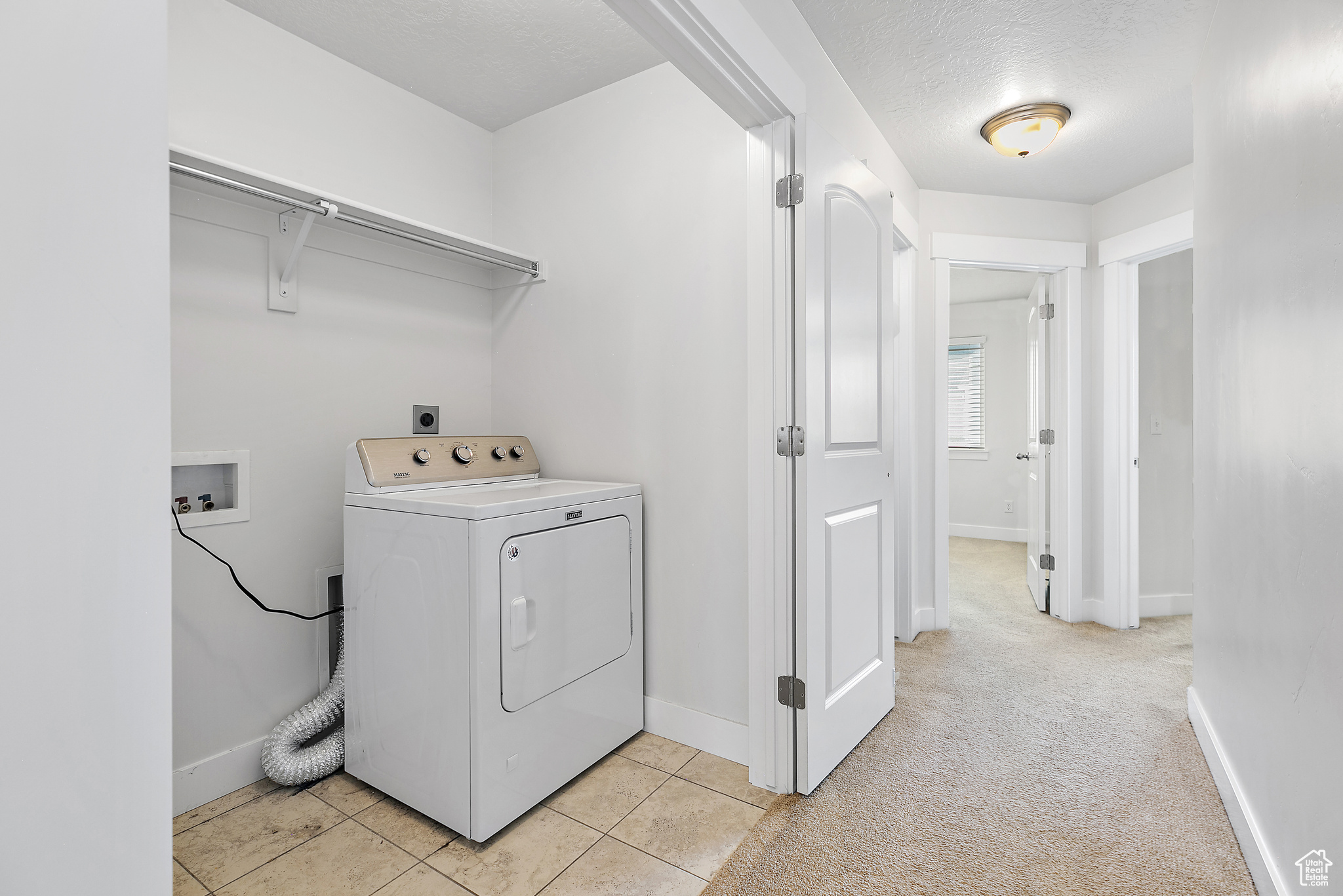 Laundry area with a textured ceiling, light carpet, and washer / dryer