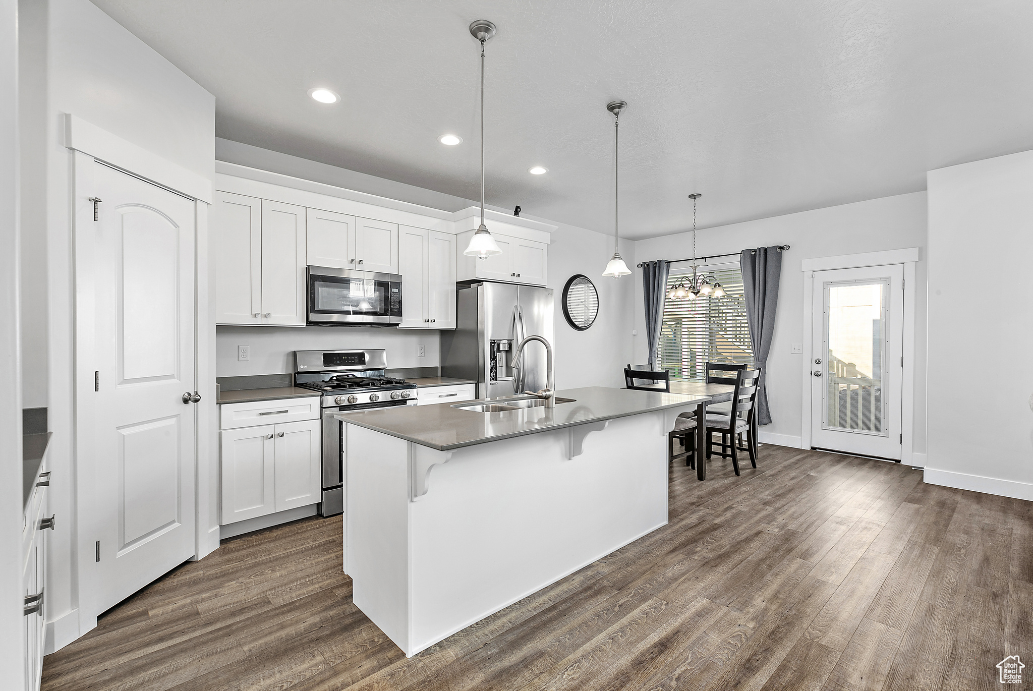 Kitchen with appliances with stainless steel finishes, wood-style flooring, white cabinets, and sink