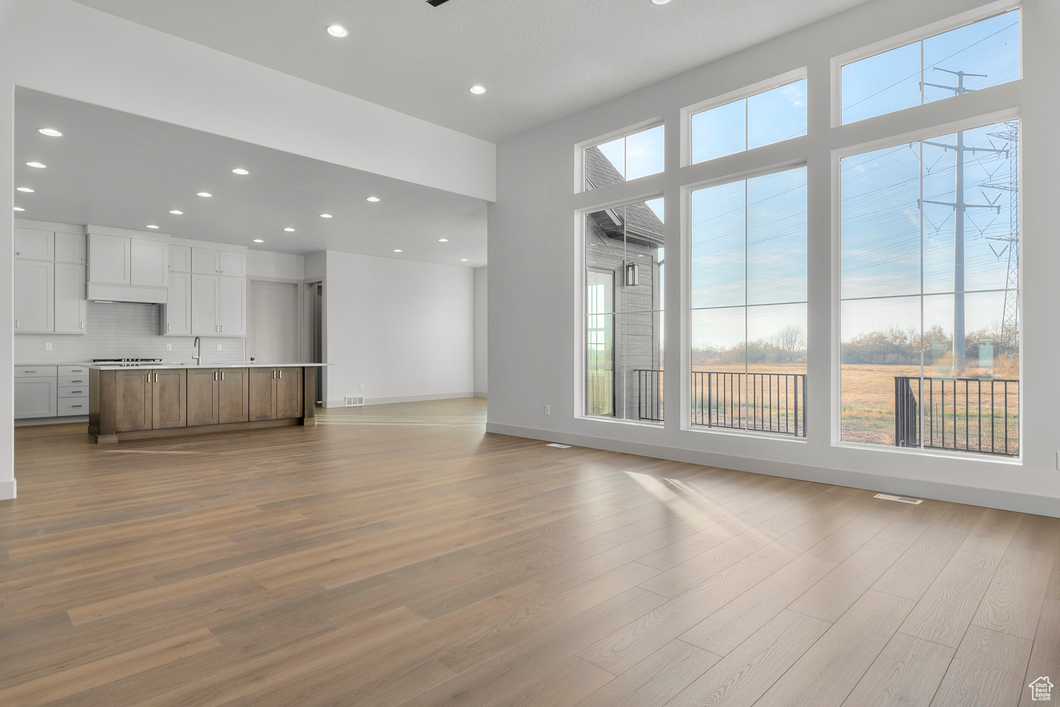 Unfurnished living room featuring light hardwood / wood-style flooring, a high ceiling, and sink