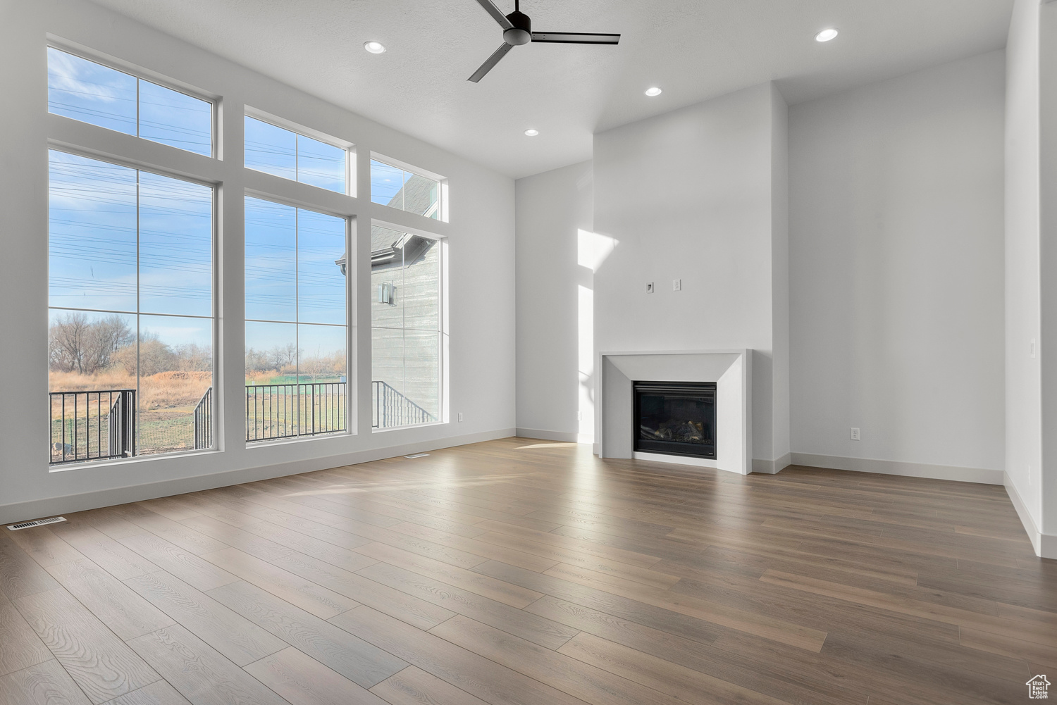 Unfurnished living room featuring wood-type flooring and ceiling fan