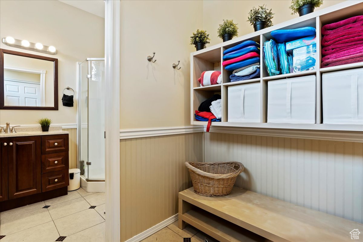 Bathroom located in the back of the garage with vanity, walk in shower, and tile patterned flooring