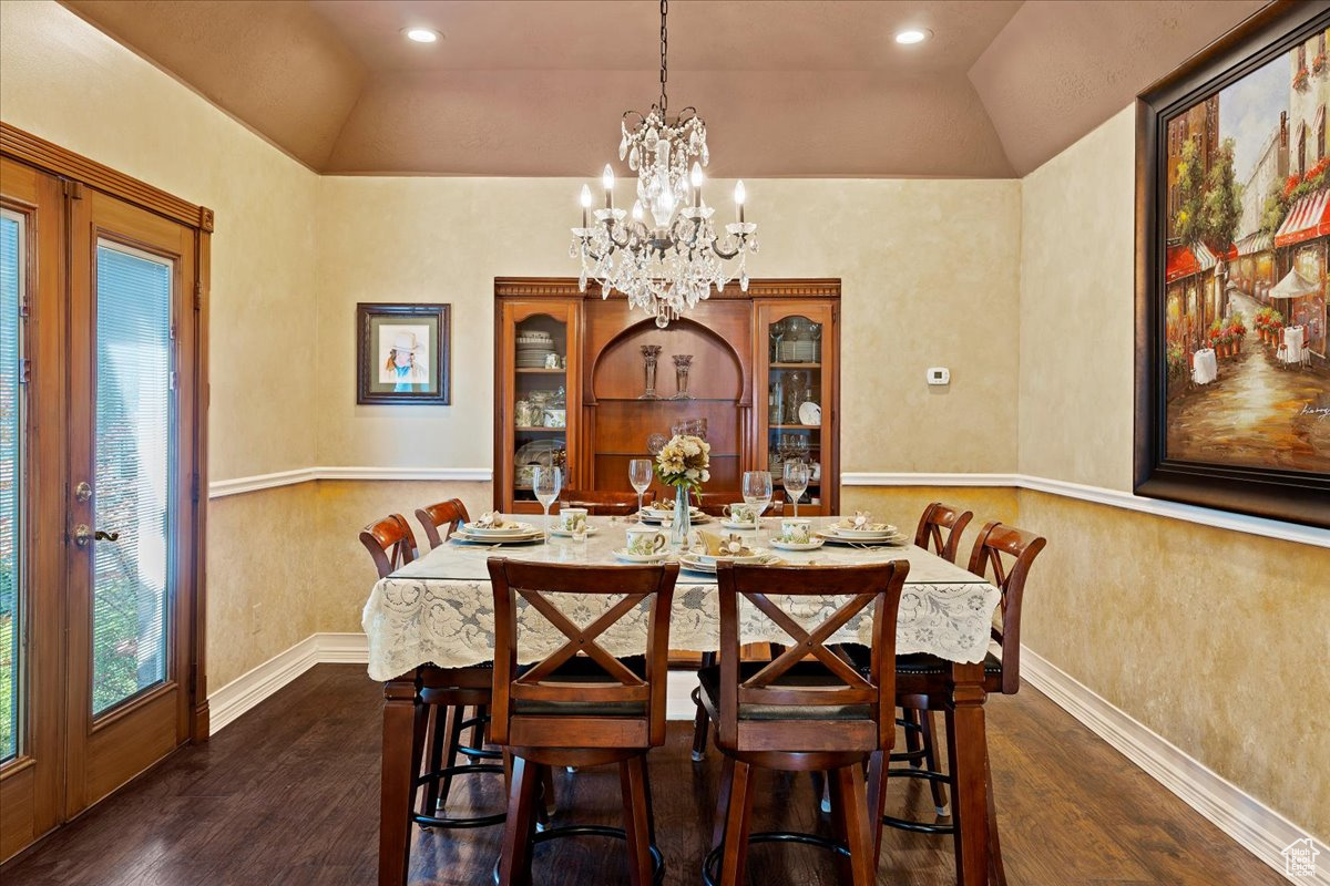 Dining space featuring vaulted ceiling, dark hardwood / wood-style flooring, and a chandelier