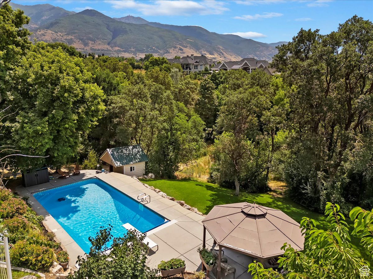 View of pool featuring a patio area, a lawn, a mountain view, and a gazebo